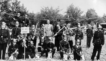 Schulbuben in historischer Feuerwehruniform, hinten Lehrer H. Jung und Georg Pfeiffer